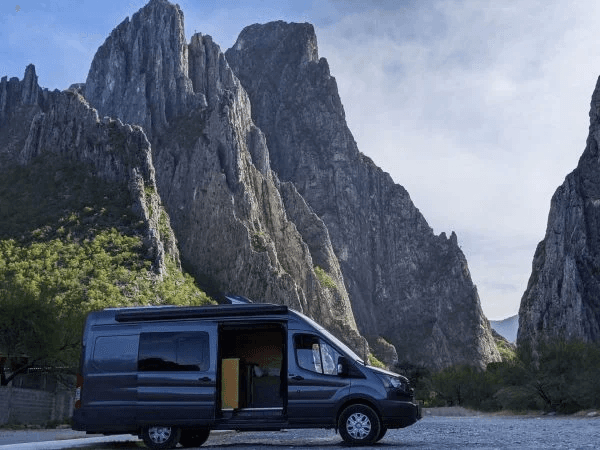 Guests enjoying breakfast with a mountain view from the back of a camper van